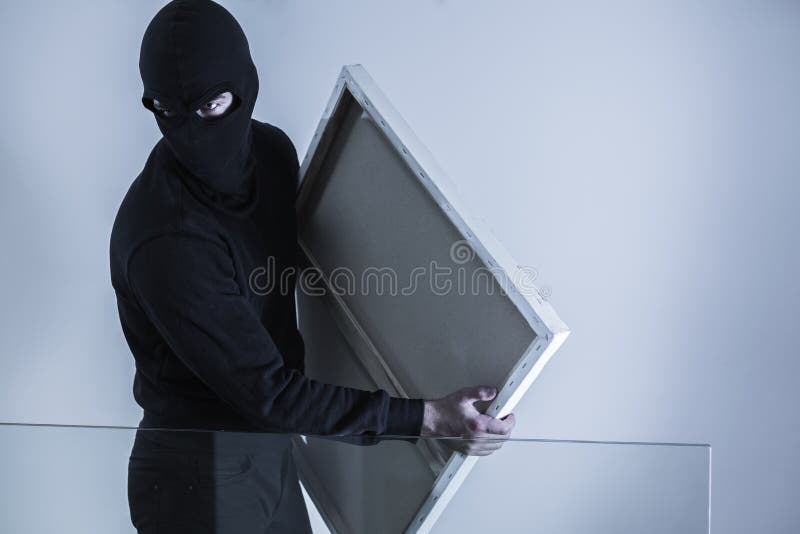 Photo of masked criminal holding stolen picture. Photo of masked criminal holding stolen picture