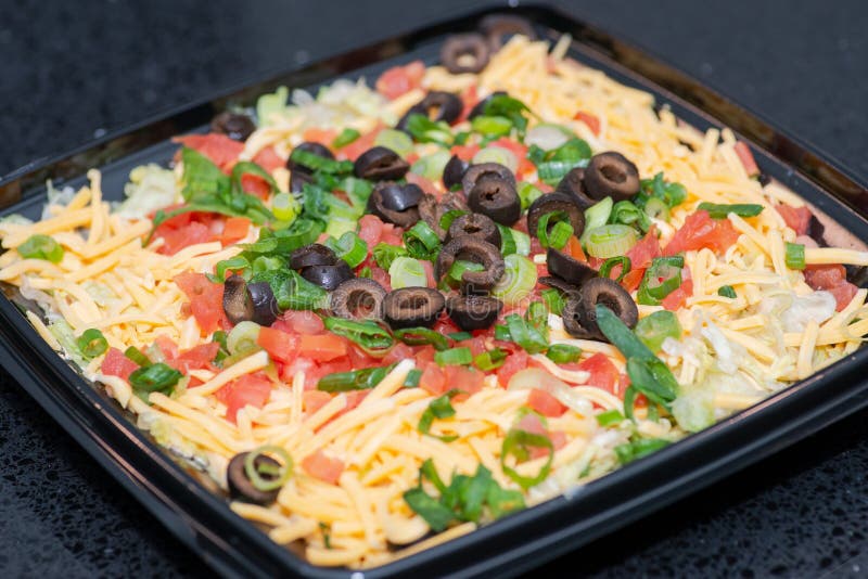 Immersione di strato del taco del partito Formaggio cremoso dal sapore caratteristico e panna acida completati con lattuga, pomod fotografia stock Immersione di strato del taco del partito Formaggio cremoso dal sapore caratteristico e panna acida completati con lattuga, pomod fotografia stock