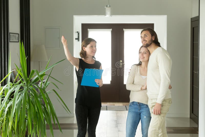 Immobilienagentur oder Designer, die Haus zu den jungen Paaren zeigen lizenzfreie stockfotografie Immobilienagentur oder Designer, die Haus zu den jungen Paaren zeigen lizenzfreie stockfotografie