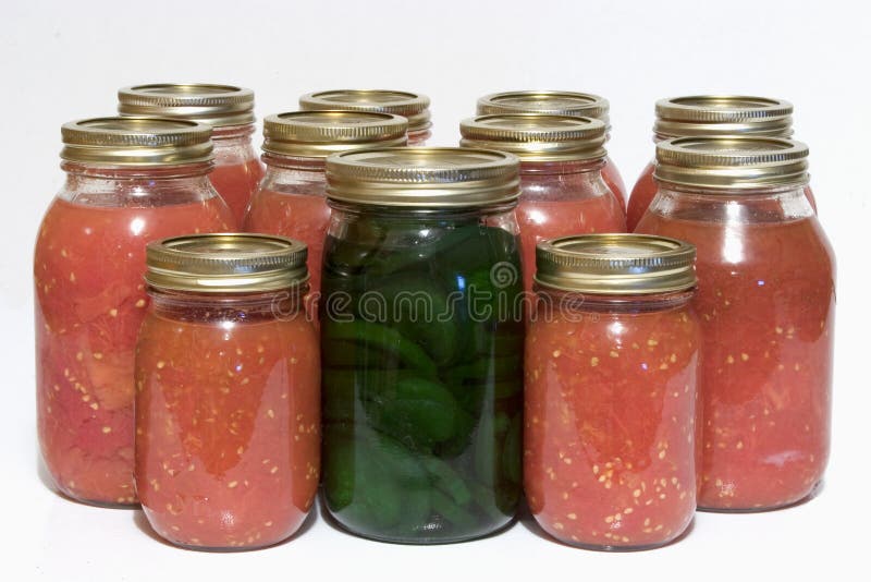 Several jars of canned tomatoes with a jar of pickels in the middle. Several jars of canned tomatoes with a jar of pickels in the middle.