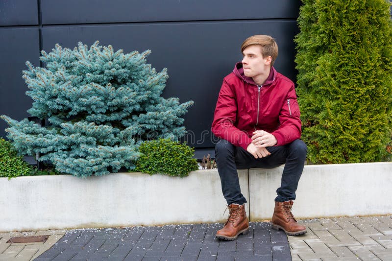 Impatient teenager boy sitting outdoor in park feeling bored stock photography Impatient teenager boy sitting outdoor in park feeling bored stock photography