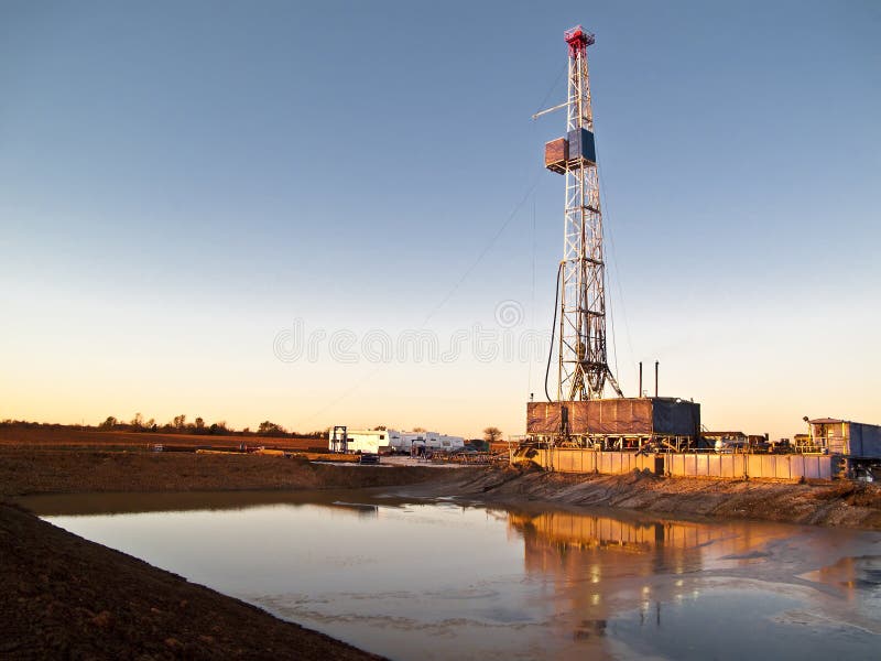 Oil drilling rig and its reflection in the mud retaining pond. Oil drilling rig and its reflection in the mud retaining pond