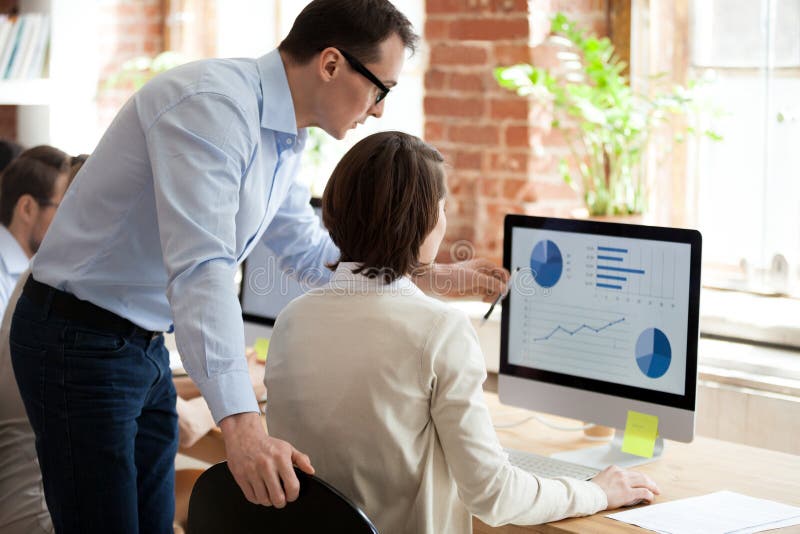Impiegato d'aiuto del responsabile esecutivo che prepara rapporto statistico online in ufficio immagini stock