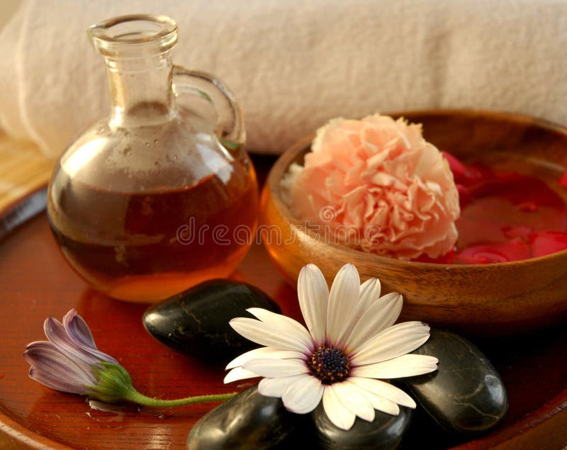 Evening spa preparations with massage oil, floral scented water, stones and towel. Evening spa preparations with massage oil, floral scented water, stones and towel