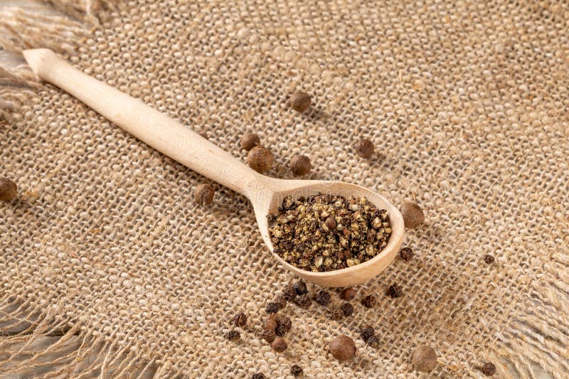 Impostazione in stile contadino con tritacarne e pepe nero macinato finemente su tovagliolo. Un'impostazione rustica in stile peasantino con un tritacarne di pepe di legno e pepe nero macinato finemente su un tovagliolo in tessuto creando un'atmosfera accogliente e invitante.