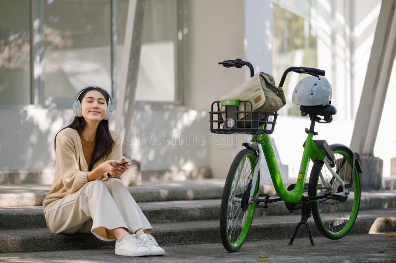 Imprenditrice asiatica va al lavoro in bancarella d'ufficio e porta con sé uno zaino sorridente con la bicicletta. pendolare in bi fotografia stock