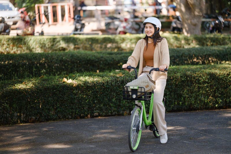 Imprenditrice asiatica va al lavoro in bancarella d'ufficio e porta con sé uno zaino sorridente con la bicicletta. pendolare in bi fotografia stock
