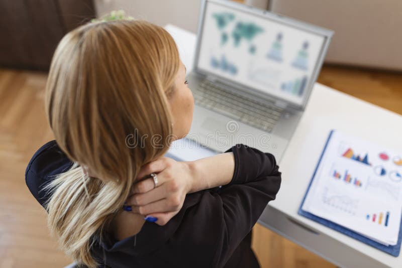 Imprenditrice che sente dolore al collo dopo essersi seduta al tavolo con un portatile. stanca donna che soffre di sindrome da uff fotografia stock libera da diritti