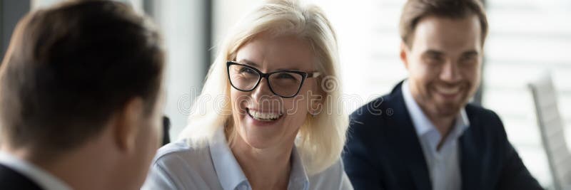 Imprenditrice di mezza età che ride goda di una conversazione amichevole durante un incontro di affari