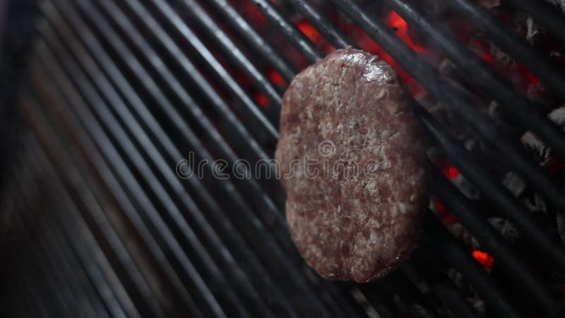 Imágenes de cierre de la hamburguesa cocinando en la parrilla con humo flotando alrededor almacen de metraje de vídeo