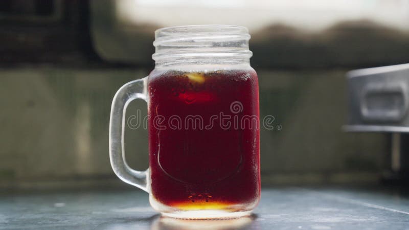 Imágenes de cierre de los cubos de hielo moviéndose en un vaso de té helado al aire libre con fondo borroso almacen de video