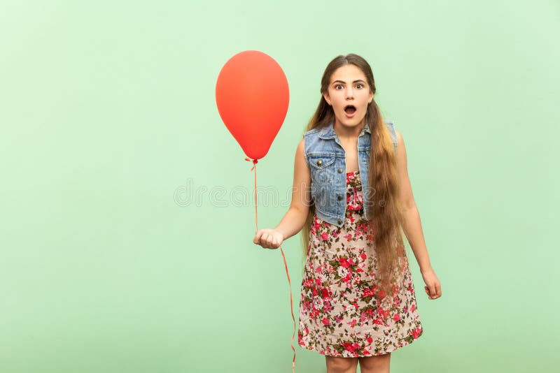 Inacreditável! O adolescente louro bonito é sho? ked, olhando a câmera, com ballon vermelho em uma luz - fundo verde imagens de stock Inacreditável! O adolescente louro bonito é sho? ked, olhando a câmera, com ballon vermelho em uma luz - fundo verde imagens de stock