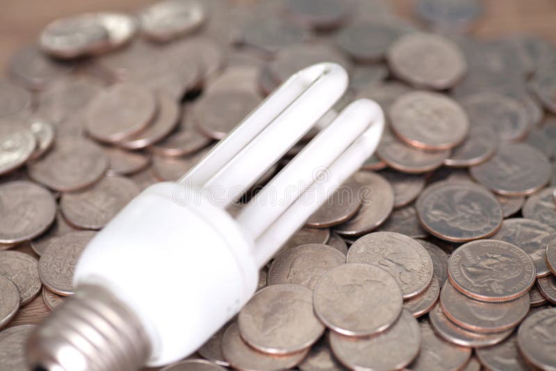 An Incandescent Light Bulb Placed on a Pile of Dollar Coins Stock Photo