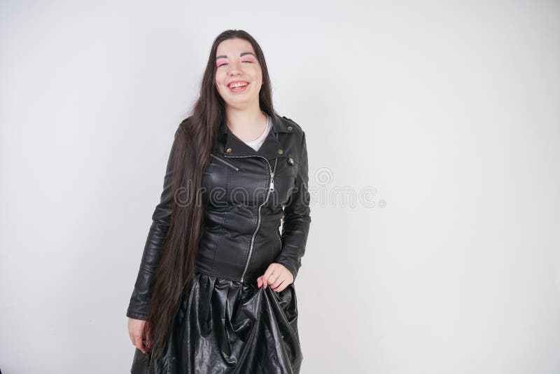Incantare castana in bomber nero nei supporti di stile della roccia con uno smartphone su un fondo bianco nello studio immagini stock libere da diritti