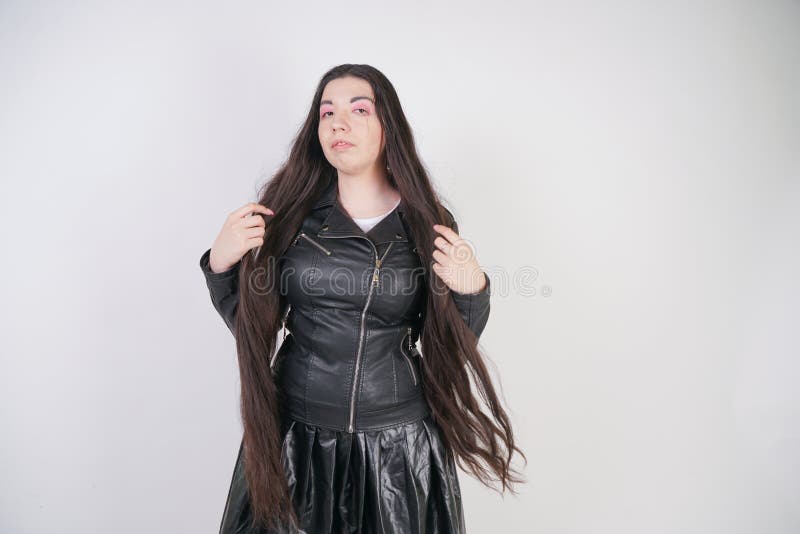 Incantare castana in bomber nero nei supporti di stile della roccia con uno smartphone su un fondo bianco nello studio fotografie stock