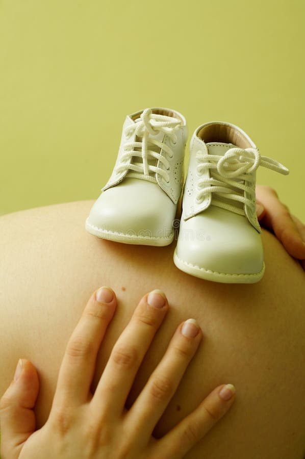 A pregnant woman with shoes of baby. A pregnant woman with shoes of baby