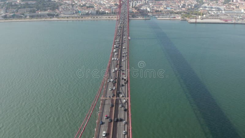 Inclinación aérea revelan tráfico vehicular transitado en carretera de varios carriles cruzando puente rojo ponte 25 de abril haci metrajes