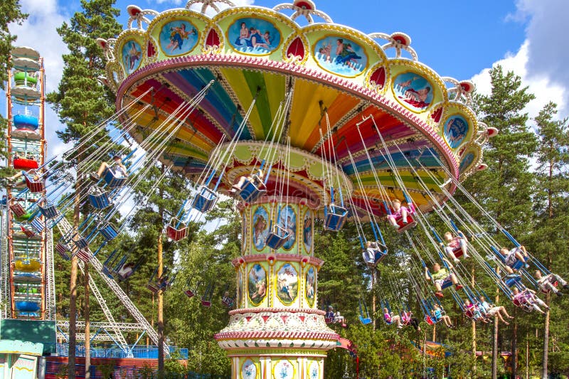 Inclinaison du tour aérien de chaise à l'annuaire, tour d'oscillation à la foire en parc d'attractions avec des pins images libres de droits Inclinaison du tour aérien de chaise à l'annuaire, tour d'oscillation à la foire en parc d'attractions avec des pins images libres de droits