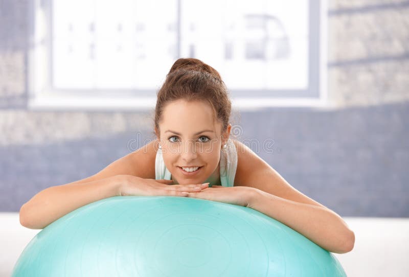 Inclinzione femminile attraente sul sorridere del fitball immagine stock Inclinzione femminile attraente sul sorridere del fitball immagine stock