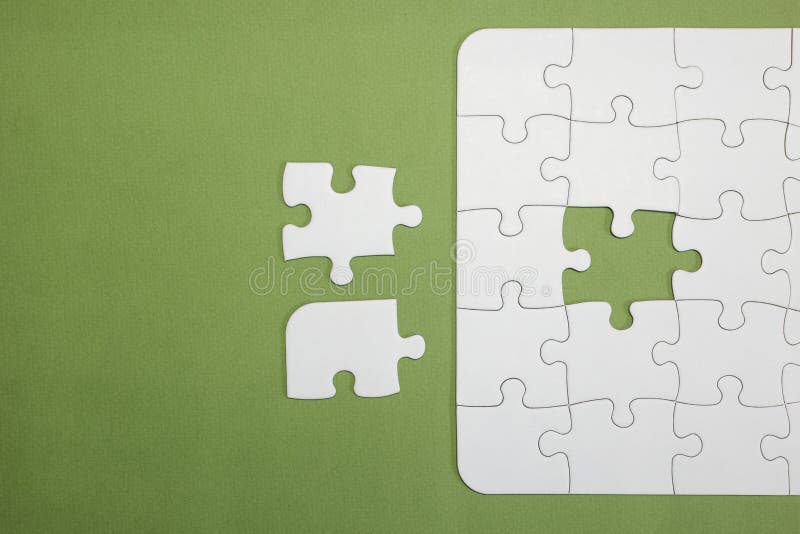 A puzzle is missing two pieces to be completed in different colors. white  pieces and one piece in green and one in orange to add text Stock Photo -  Alamy