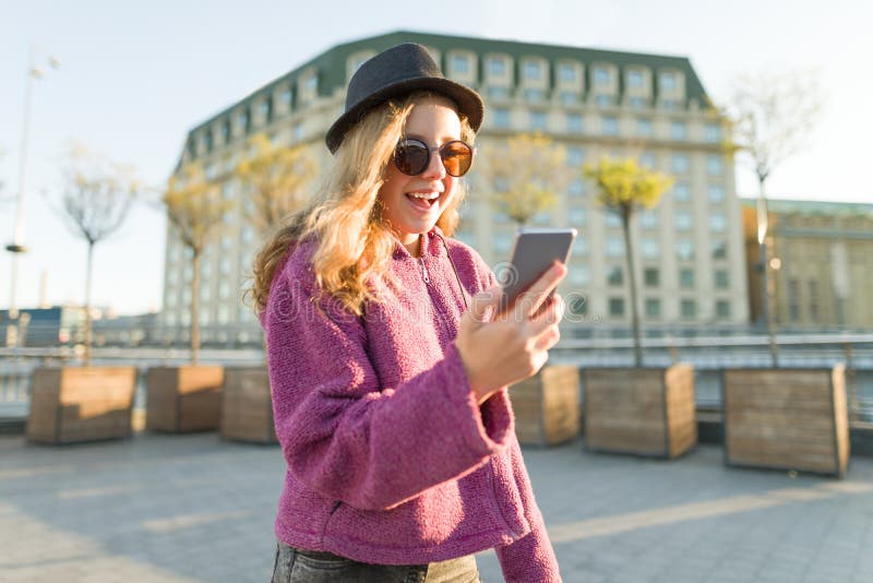 Inconformista adolescente de la muchacha en sombrero y vidrios con el teléfono móvil imagenes de archivo Inconformista adolescente de la muchacha en sombrero y vidrios con el teléfono móvil imagenes de archivo