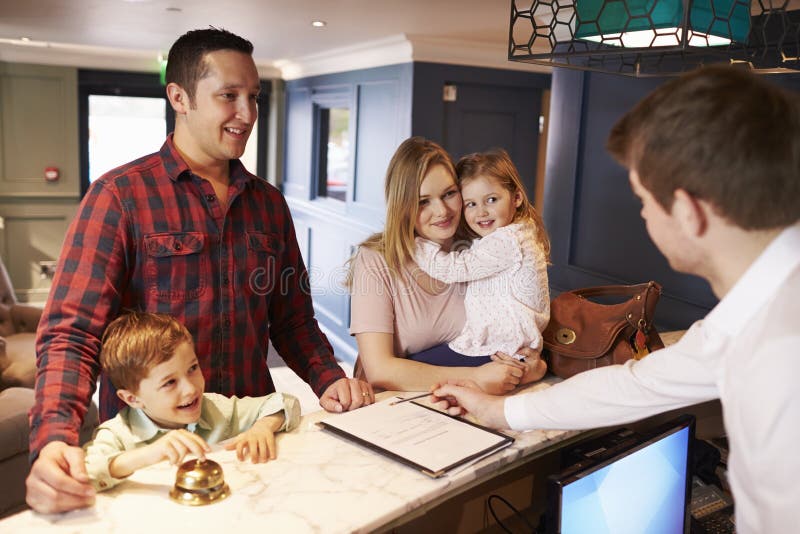 Family Checking In At Hotel Reception Desk. Family Checking In At Hotel Reception Desk