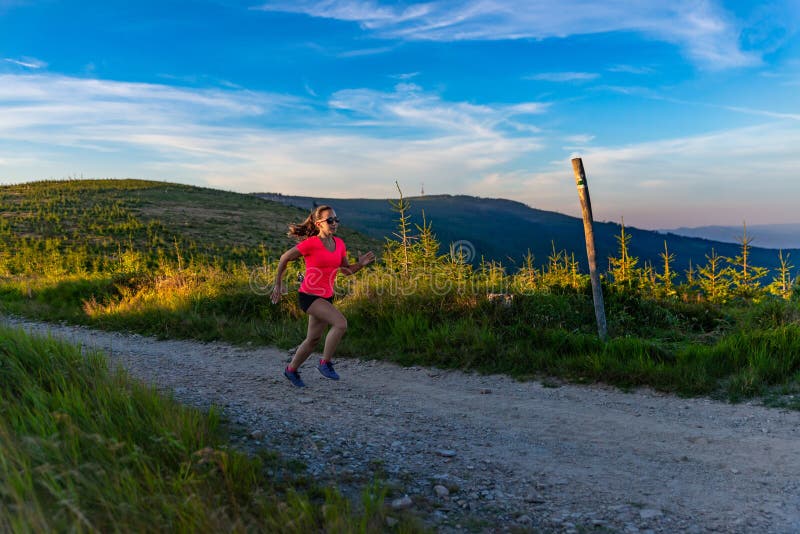Incrocio della giovane donna che corre in montagne all'estate immagini stock Incrocio della giovane donna che corre in montagne all'estate immagini stock