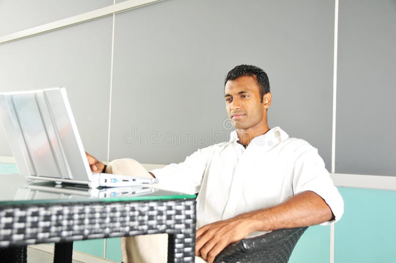 Indian Asian Man looking at his laptop outdoors