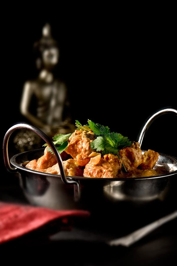 Classic Indian buttered chicken with roasted coriander, tomatoes and honey with a rich marinade coconut sauce set against a dark Indian styled background. Copy space. Classic Indian buttered chicken with roasted coriander, tomatoes and honey with a rich marinade coconut sauce set against a dark Indian styled background. Copy space.