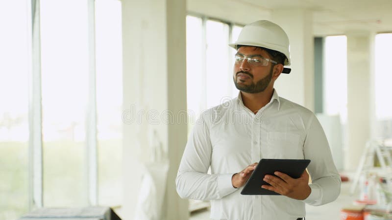 Indian construction engineer reviewing building project with tablet on-site stock video
