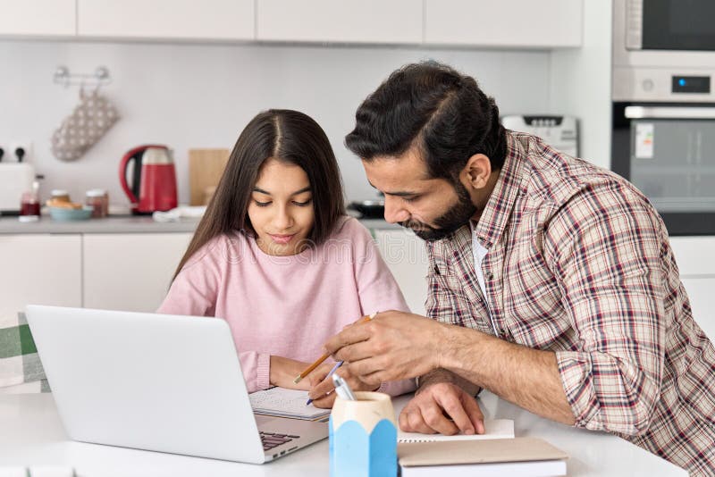 Indian parent dad helping school child teen daughter studying online at home.