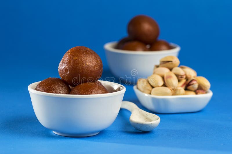 Indian Dessert Gulab Jamun in Bowl with Spoon on Blue Background