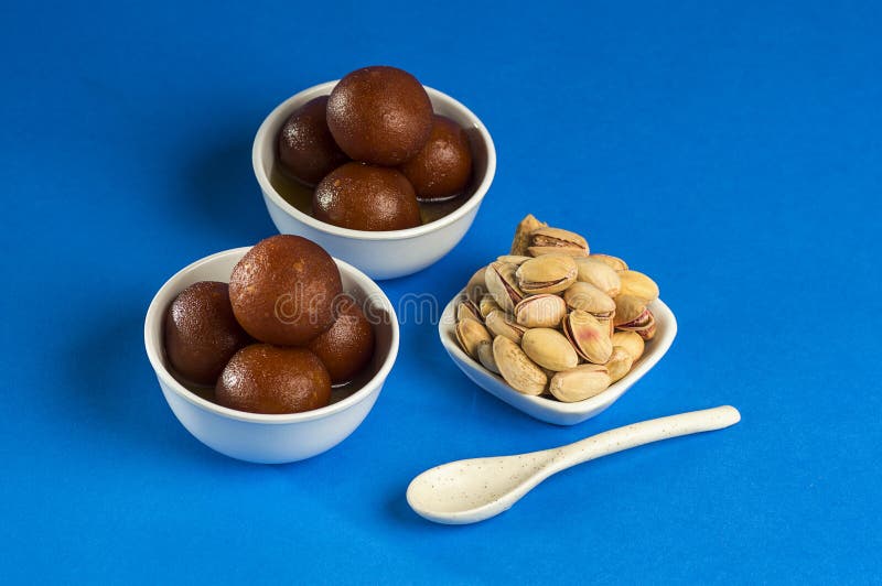 Indian Dessert Gulab Jamun in Bowl with Spoon on Blue Background