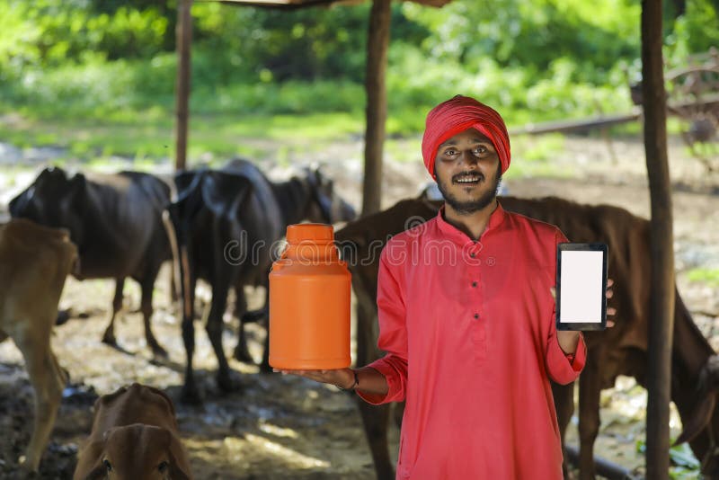 Indian farmer holding milk bottle in hand and showing mobile phone blank screen