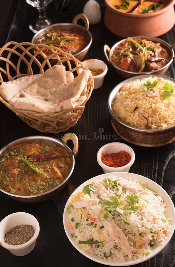 Indian food ;curries, chapathi, fried rice and biriyani on a black marble background.