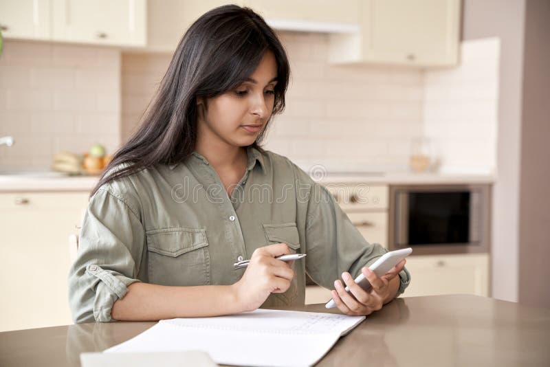 Indian girl holding mobile phone using online education app at home.