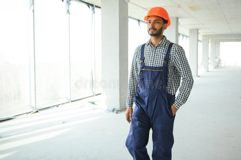 Indian male construction worker standing in uniform and hard hat at construction site. stock image