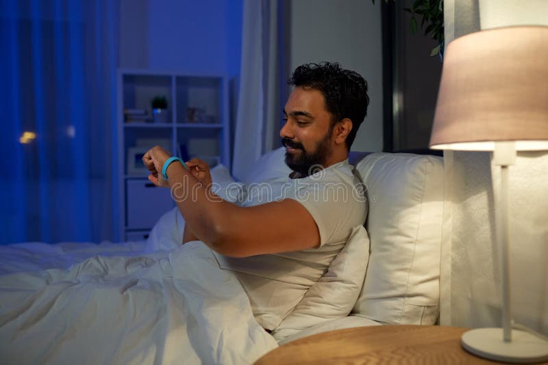 indian man with health tracker in bed at night