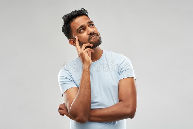 Doubts and people concept - indian man thinking and looking up over grey background