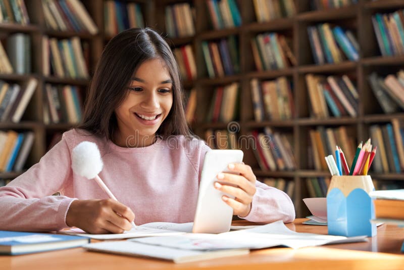 Indian school girl holding phone distance learning using mobile application. stock photo
