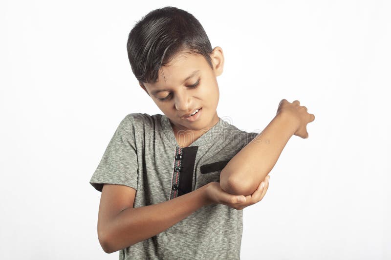 Indiansk pojke med armbågssmärta som håller handen tätt i vit bakgrund. Barn som lider av armbågssmärta i vit bakgrund