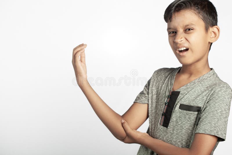 Indiansk pojke med armbågssmärta som håller handen tätt i vit bakgrund royaltyfri fotografi