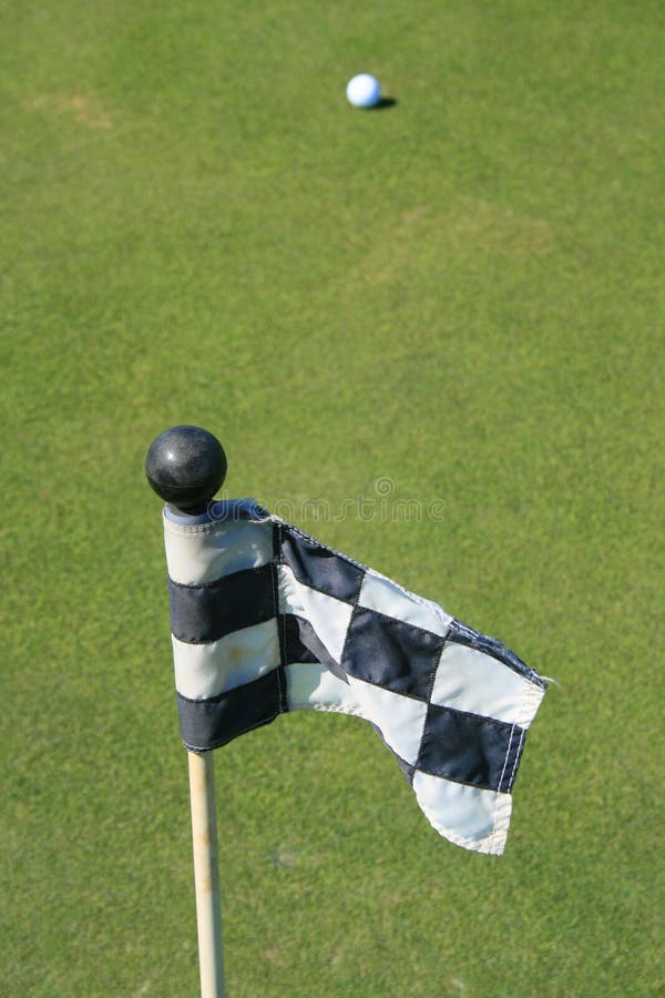 Close up of a golf course flag and a golf ball. Close up of a golf course flag and a golf ball.
