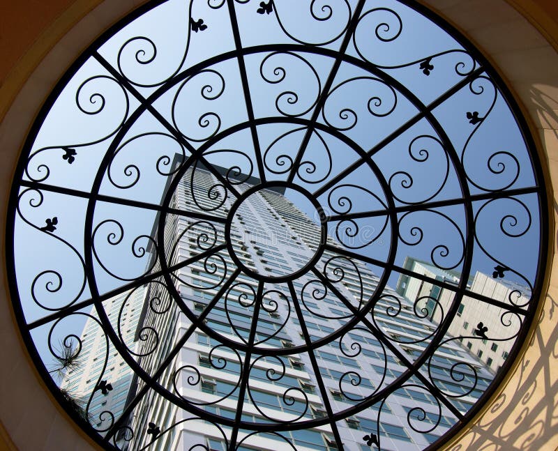 Apartments framed by a wrought iron window in the roof of an outdoor pavilion. Apartments framed by a wrought iron window in the roof of an outdoor pavilion.