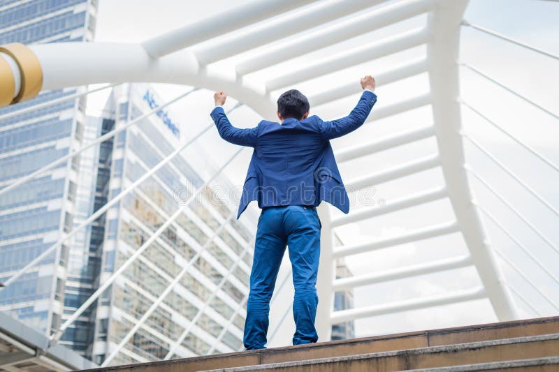 Indietro del supporto asiatico dell'uomo d'affari e di sollevare sulle mani ha celebrato il suo riuscito nella carriera e nella m fotografie stock libere da diritti Indietro del supporto asiatico dell'uomo d'affari e di sollevare sulle mani ha celebrato il suo riuscito nella carriera e nella m fotografie stock libere da diritti