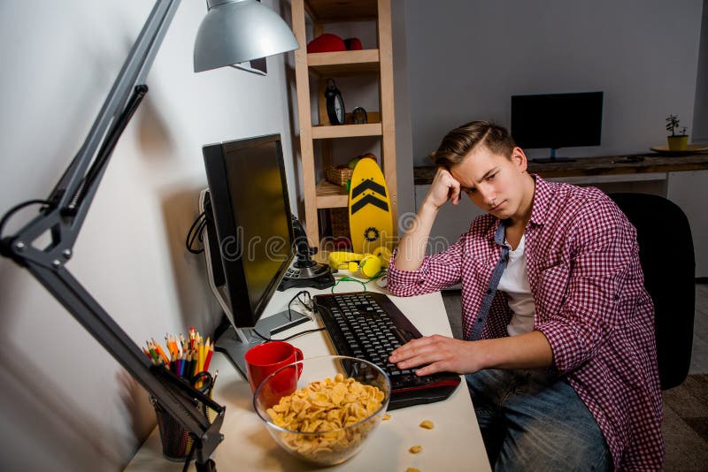 Indifferent teenage boy sitting at the table in his room. royalty free stock image Indifferent teenage boy sitting at the table in his room. royalty free stock image