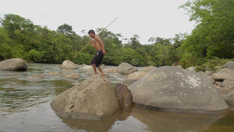 Indigenous hunter trying to fish with a spear in the amazon rainforest