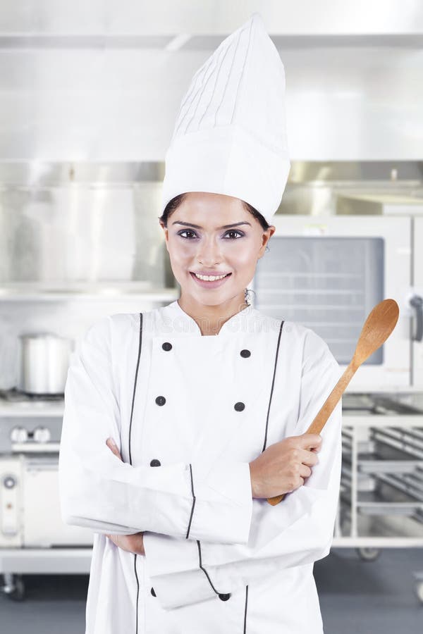 Indische chef-kok die houten lepel in keuken houden stock fotografie Indische chef-kok die houten lepel in keuken houden stock fotografie