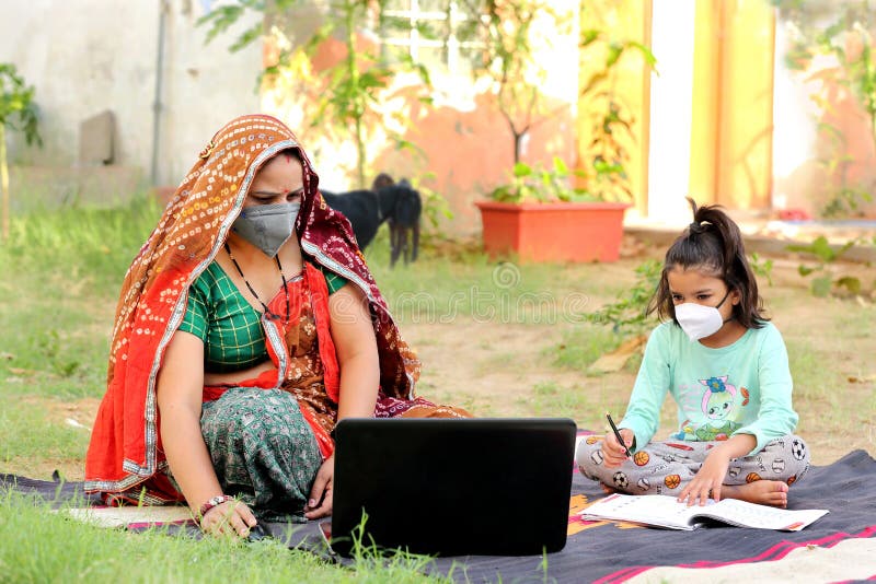 Indische ländliche Mutterunterrichtstochter online auf Notebook mithilfe des Internets.