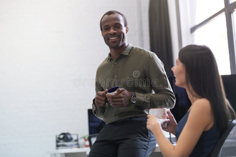 Individuo afroamericano feliz que charla con un colega femenino imagen de archivo libre de regalías Individuo afroamericano feliz que charla con un colega femenino imagen de archivo libre de regalías
